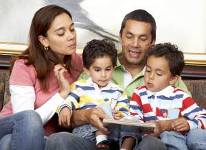 family lifestyle portrait of a mum and dad with their two kids reading a book indoors